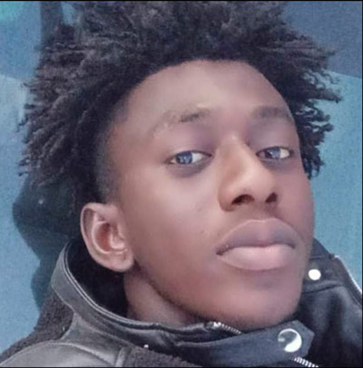A close-up selfie of a man in a black jacket