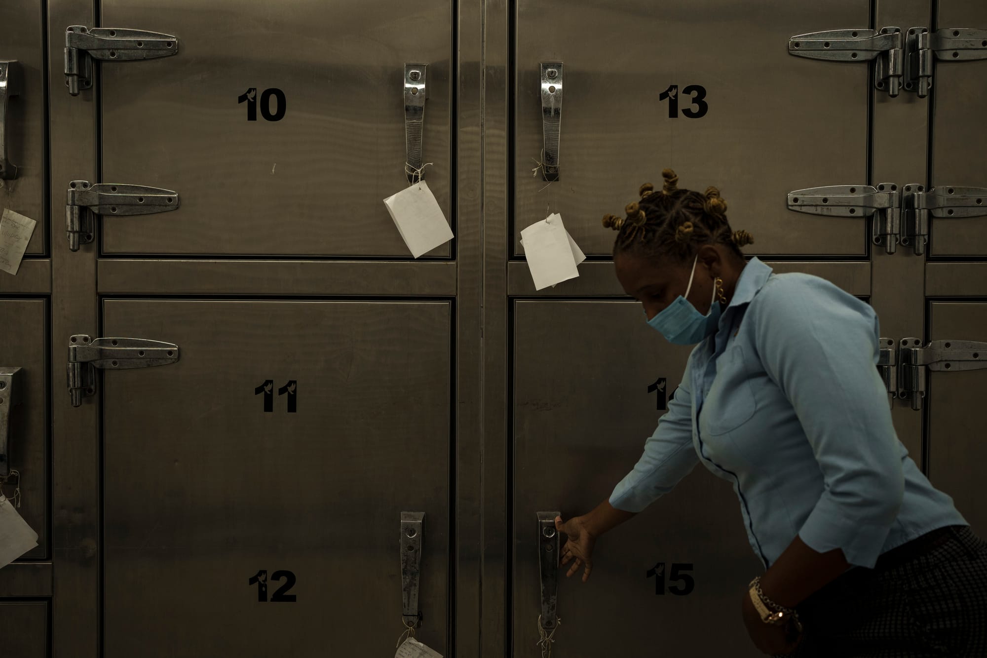 A woman bends down in front of a row of numbered evidence lockers.